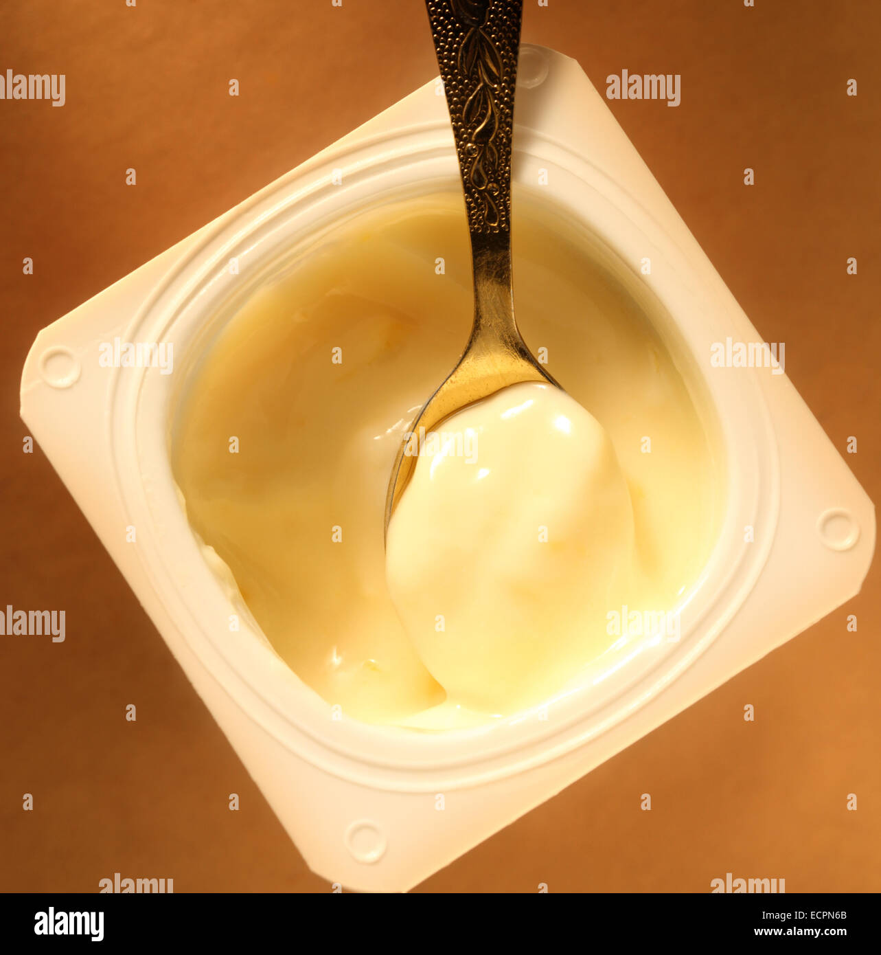 Yogurt pot with full spoon in closeup Stock Photo