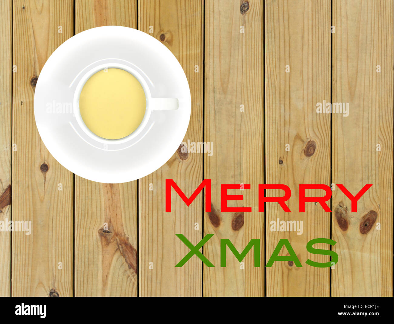 Cup of egg nog and saucer on wood background with words MERRY XMAS in red and green letters. Stock Photo