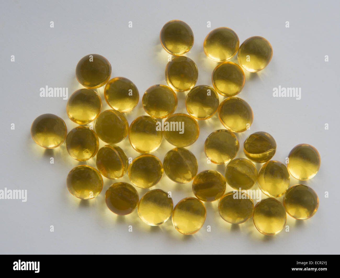 Many transparent yellow pills (capsule) are situated on the white background. Stock Photo