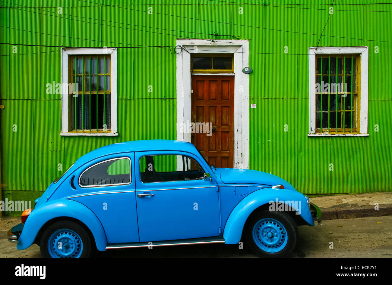 Bright blue volkswagen beetle in front of a green house in Valparaiso Chile, South america Stock Photo