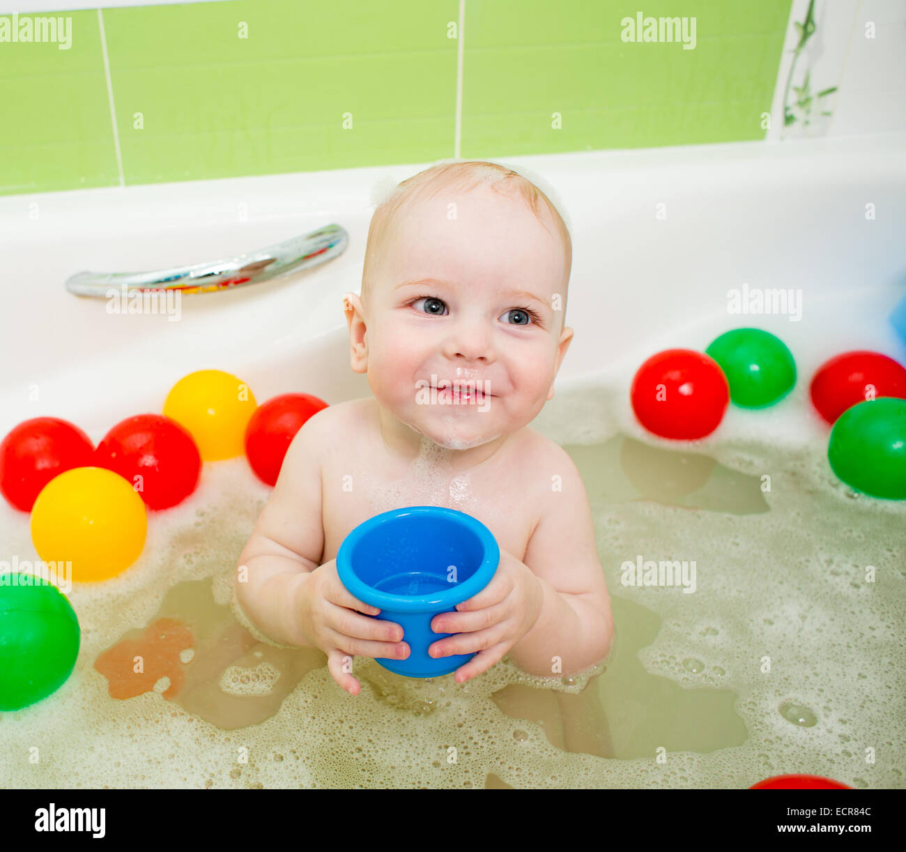 baby clapping hands and smiling while taking a bath Stock Photo