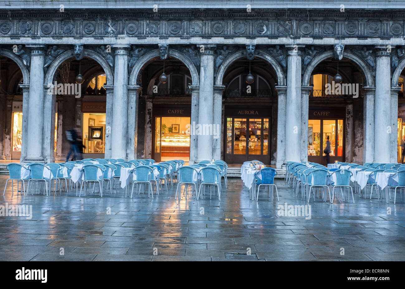 Rainy nighttime at St Mark's Square, Venice, Italy, with a cafe which has laid out tables and chairs outdoors Stock Photo