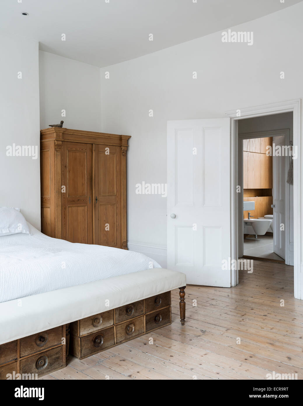 Large White Bed In Minimal White Bedroom With Wooden Wardrobe And