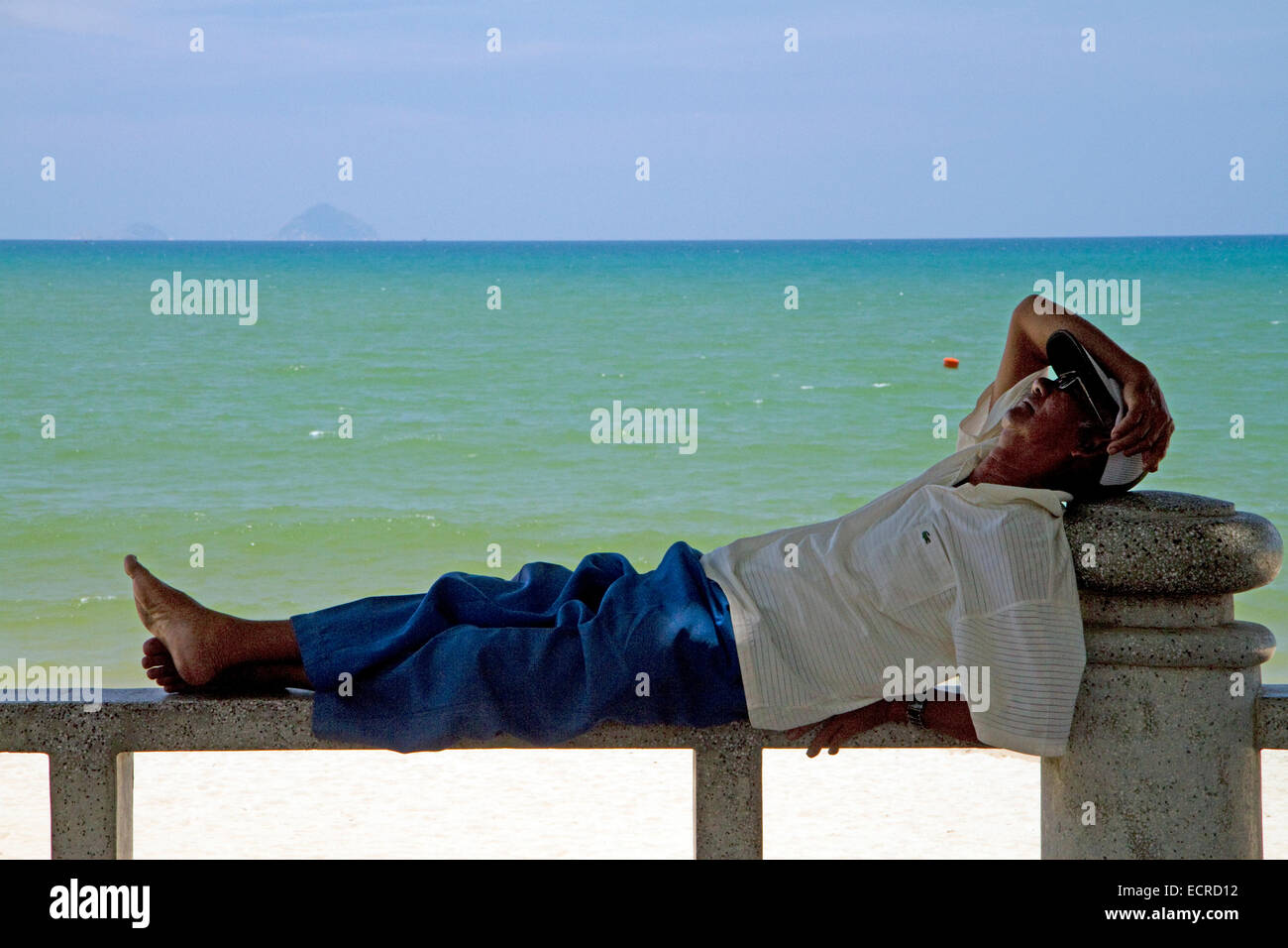 Man taking a nap on a bench at the beach in Nha Trang, Vietnam. Stock Photo