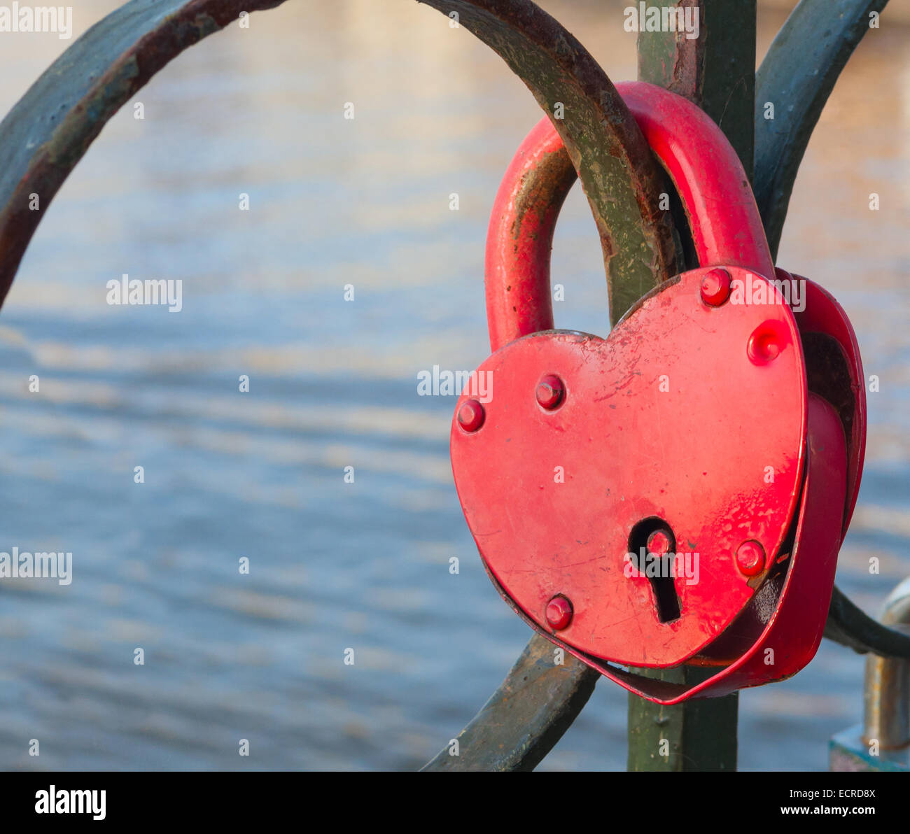 Aged rusty locked heart shaped padlock on metal railing Stock Photo