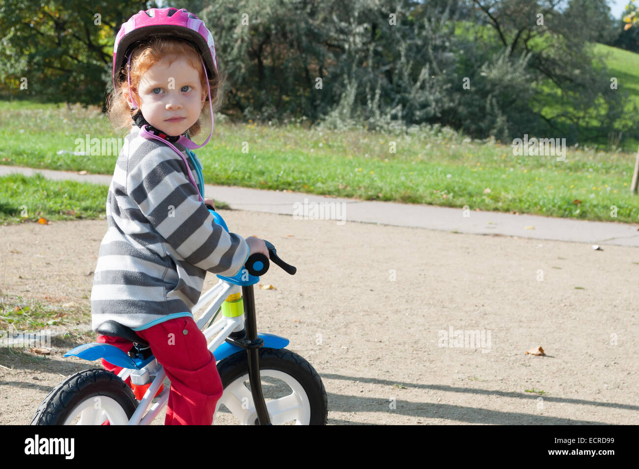 Child girl with the safety helmet on the bike in the autumn park Stock Photo