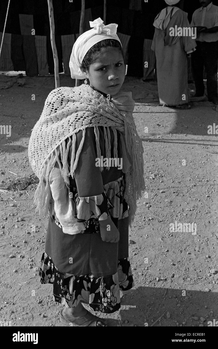 MIDDLE ATLAS MOUNTAIN, MOROCCO - JULY, 1979 – A girl shoulder her back to his younger brother in a Berber market on July, 1979, Stock Photo