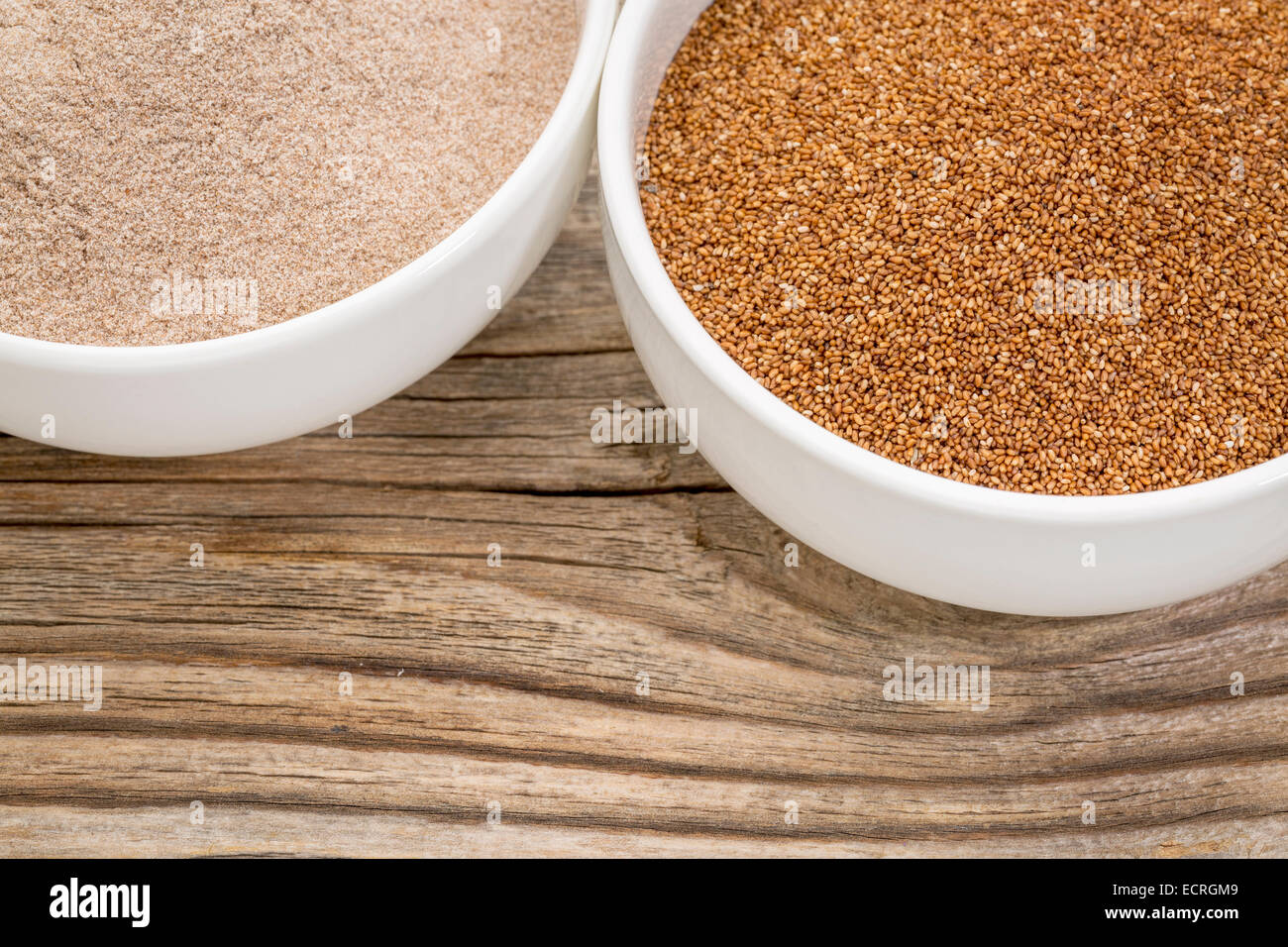 teff grain and flour in small ceramic bowls against grained wood background Stock Photo
