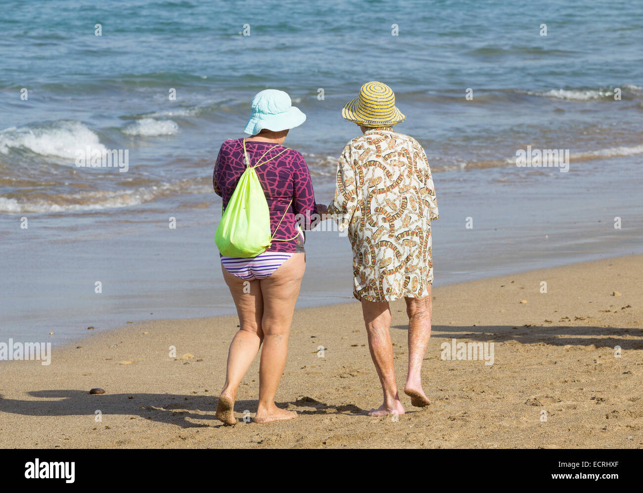 Elderly Spanish women walking and talking on beach in Spain Stock Photo