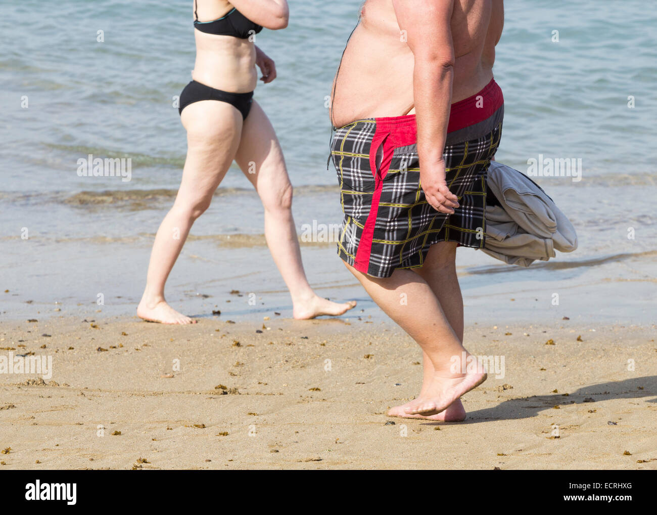 Obese man walking on beach Stock Photo