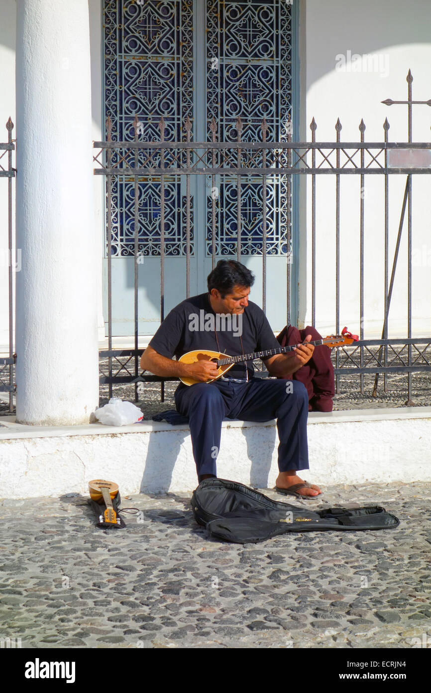 Seated man in black playing music, bouzouki Stock Photo