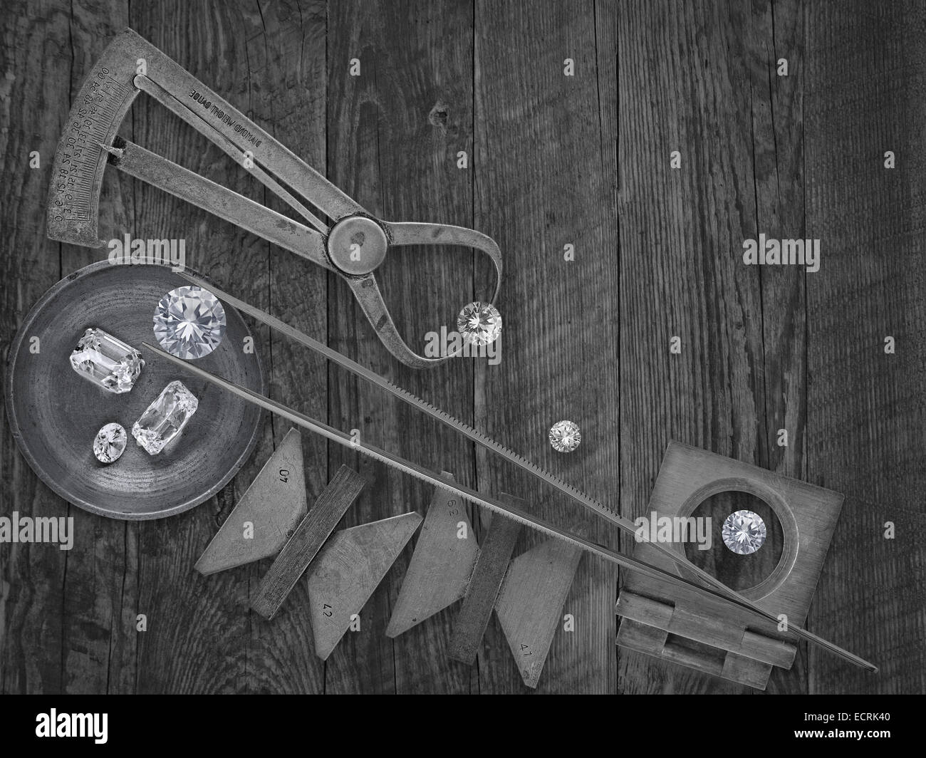black and white image of a vintage jeweler tools and diamonds over wooden bench, space for text Stock Photo