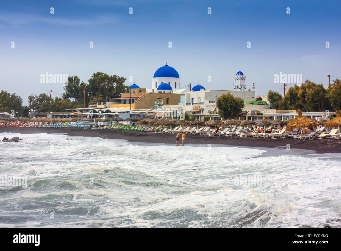 Stormy sea, beach with loungers and blue dome of Greek Orthodox church Stock Photo