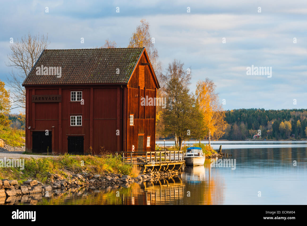 Red barn with a boat and a dock on the lake Stock Photo