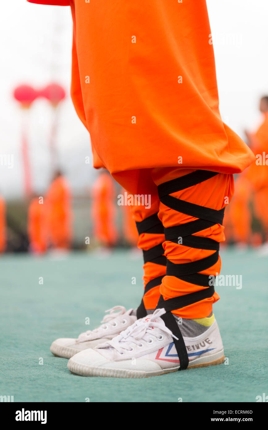 Shaolin Kung Fu student wearing Feiyue shoes and orange uniforml in DengFeng, Henan, China 2014 Stock Photo