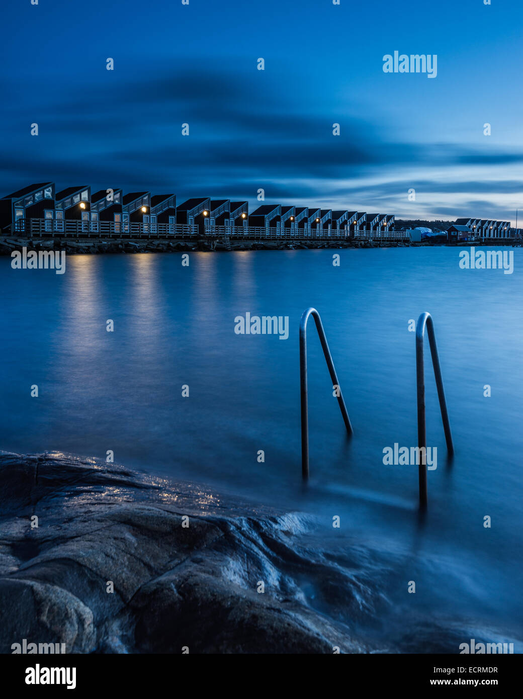 Ladder in the water and a row of shelters along the coast at night Stock Photo