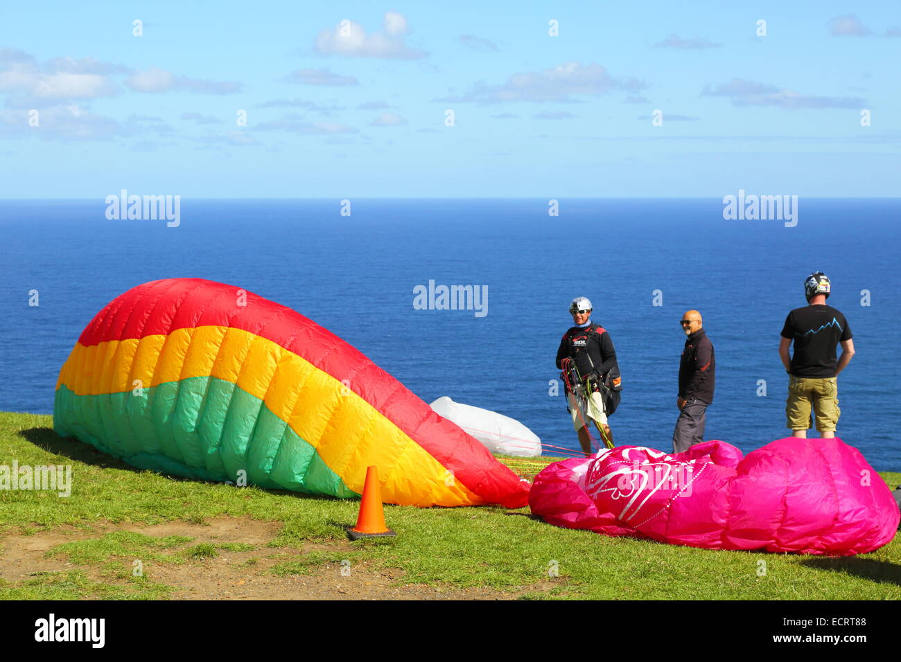 Men preparing paragliders to soar over the Pacific Ocean off Bald Hill, New South Wales, Australia. Stock Photo