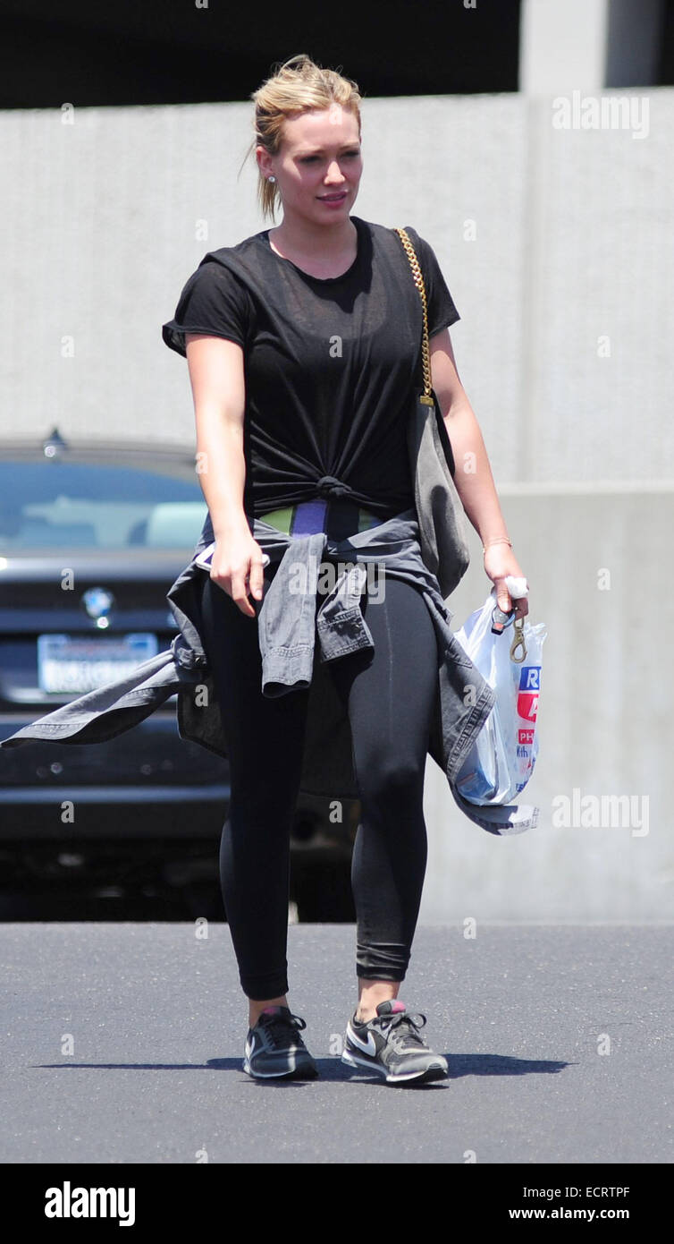 Hilary Duff wearing black sportswear with a grey sweater tied round her  waist out and about