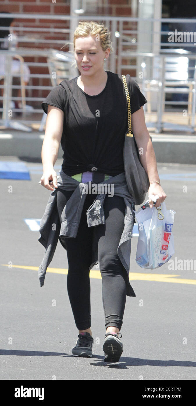 Hilary Duff wearing black sportswear with a grey sweater tied round her  waist out and about