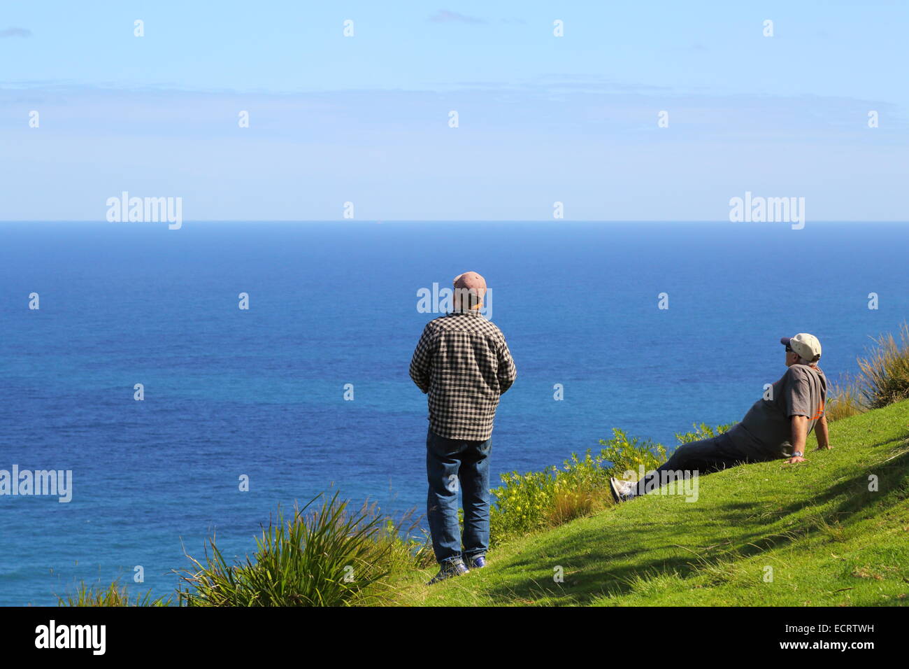 Two middle-aged men flying remote controlled gliders from a cliff along next to the Pacific Ocean, NSW, Australia. Stock Photo