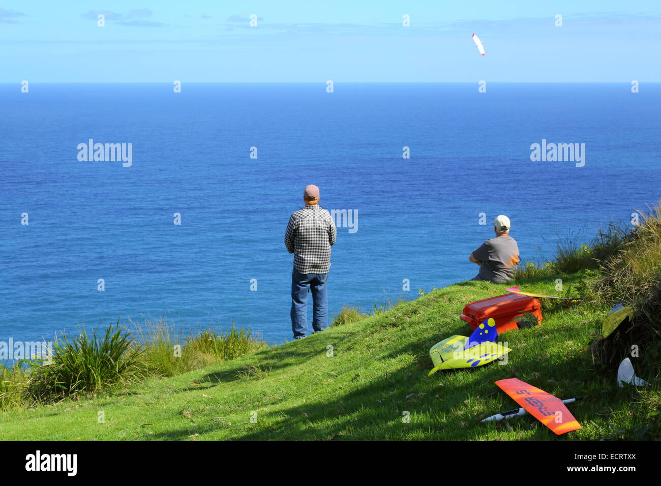 Two middle-aged men flying remote controlled gliders from a cliff along next to the Pacific Ocean, NSW, Australia. Stock Photo