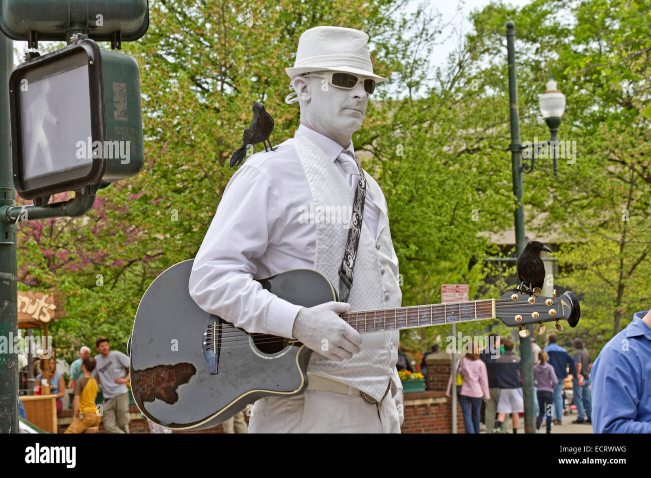 The Man in White, a living statue with crows perched on him, remains immobile then plays his guitar when given a tip Stock Photo