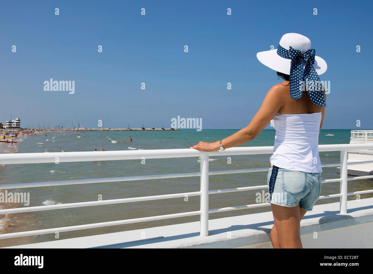 Woman with hat standing at railing on the beach, Adriatic, Senigallia, Province of Ancona, Marche, Italy Stock Photo
