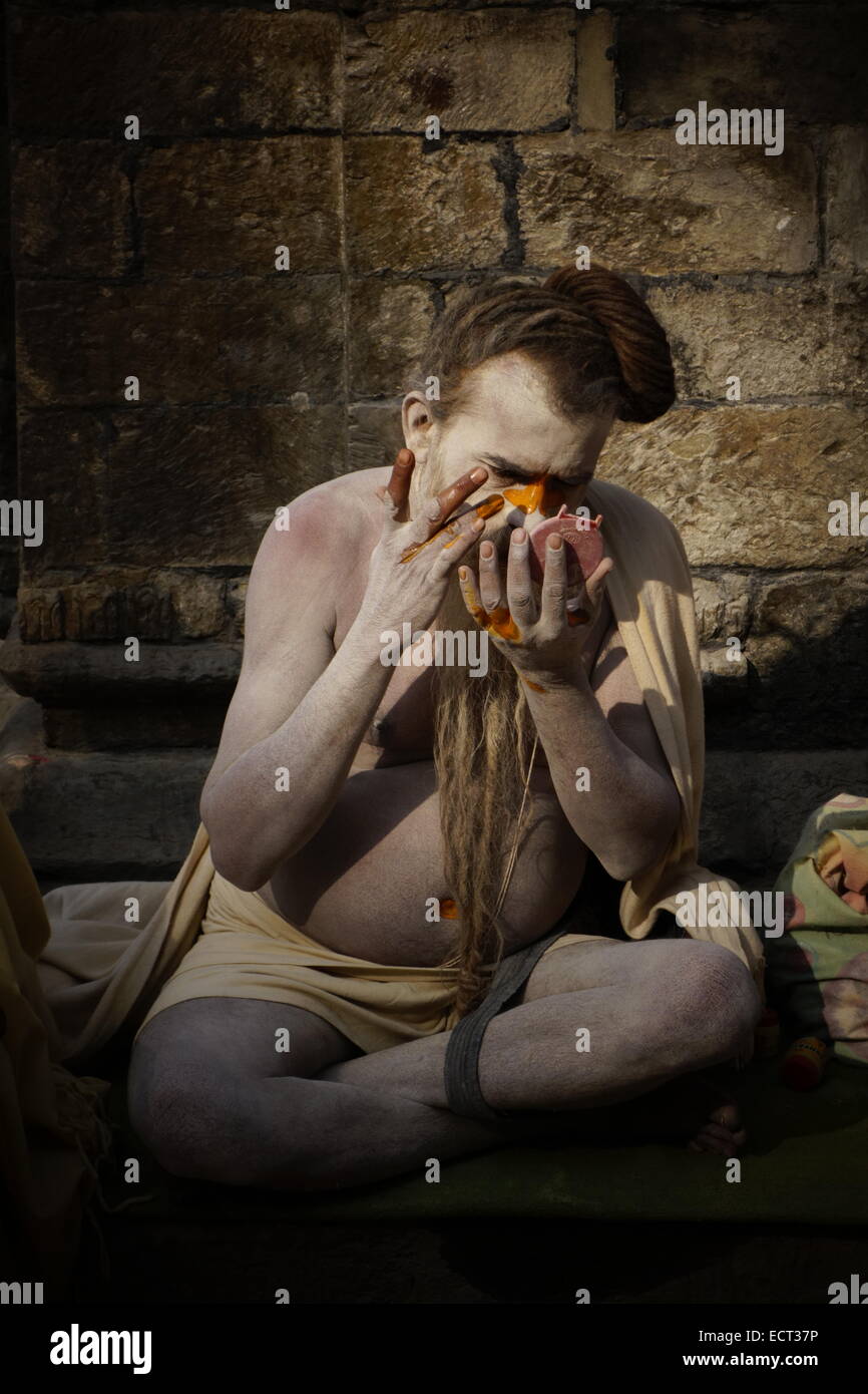 An Aghori ascetic Shaiva sadhu covering his face with ash and paint at Pashupatinath Temple which is on UNESCO World Heritage Sites list in Kathmandu Nepal Stock Photo