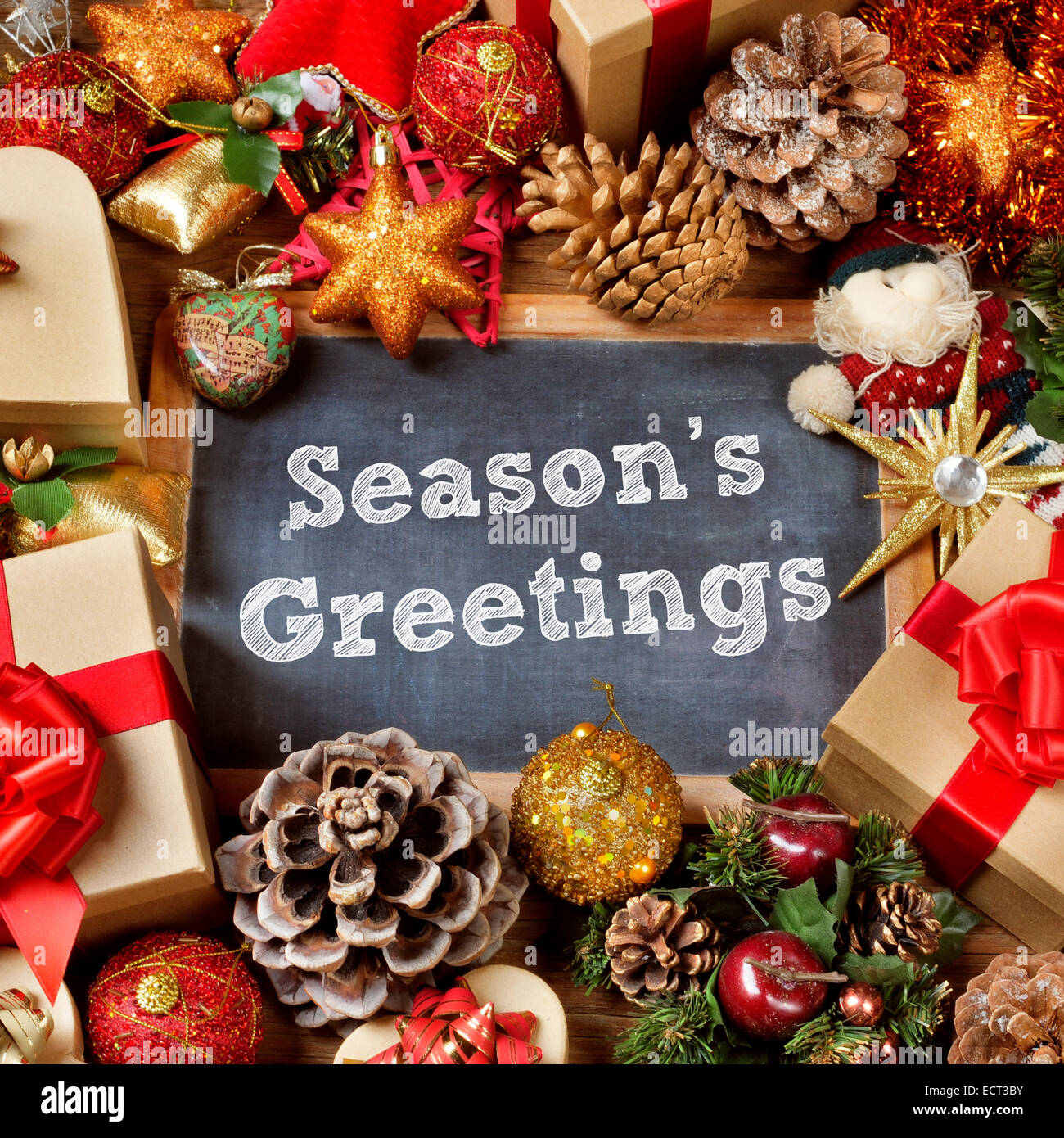 the text seasons greetings written in a chalkboard surrounded by some gifts and a pile of different christmas ornaments, such as Stock Photo