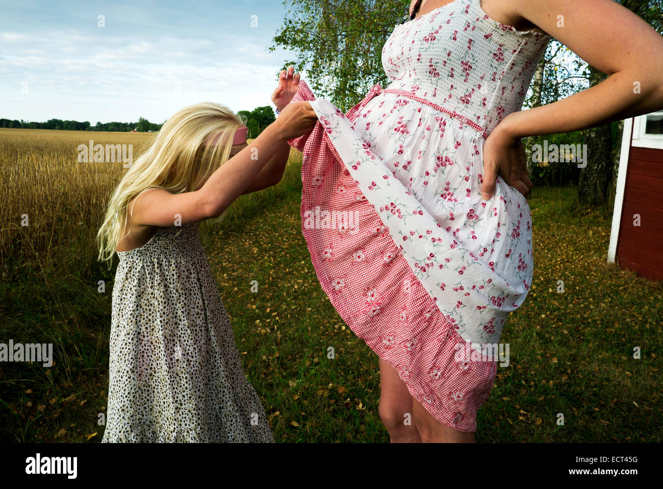 girl looking under her mothers dress to ...