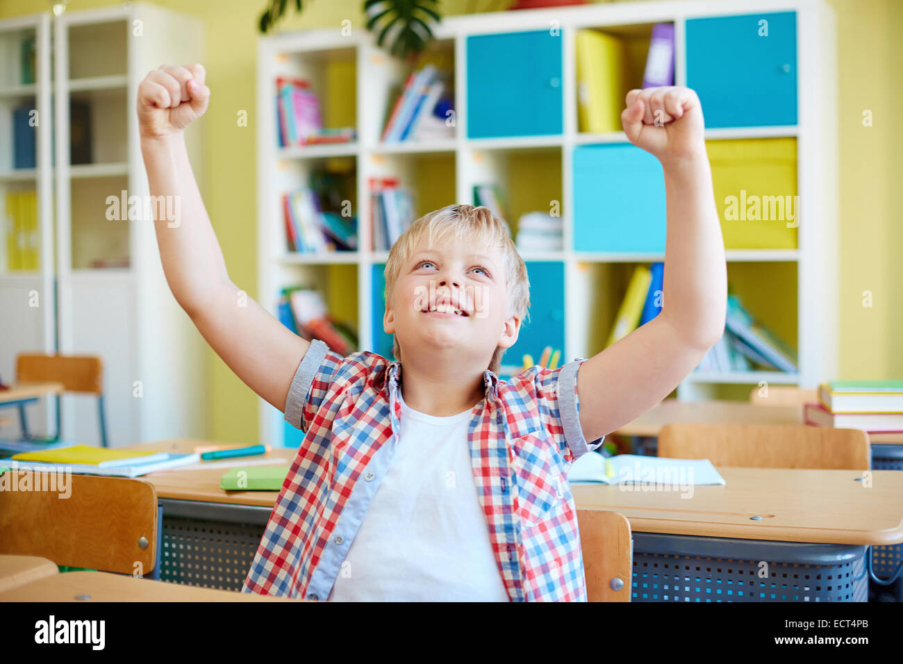 Ecstatic schoolboy expressing gladness by his workplace Stock Photo