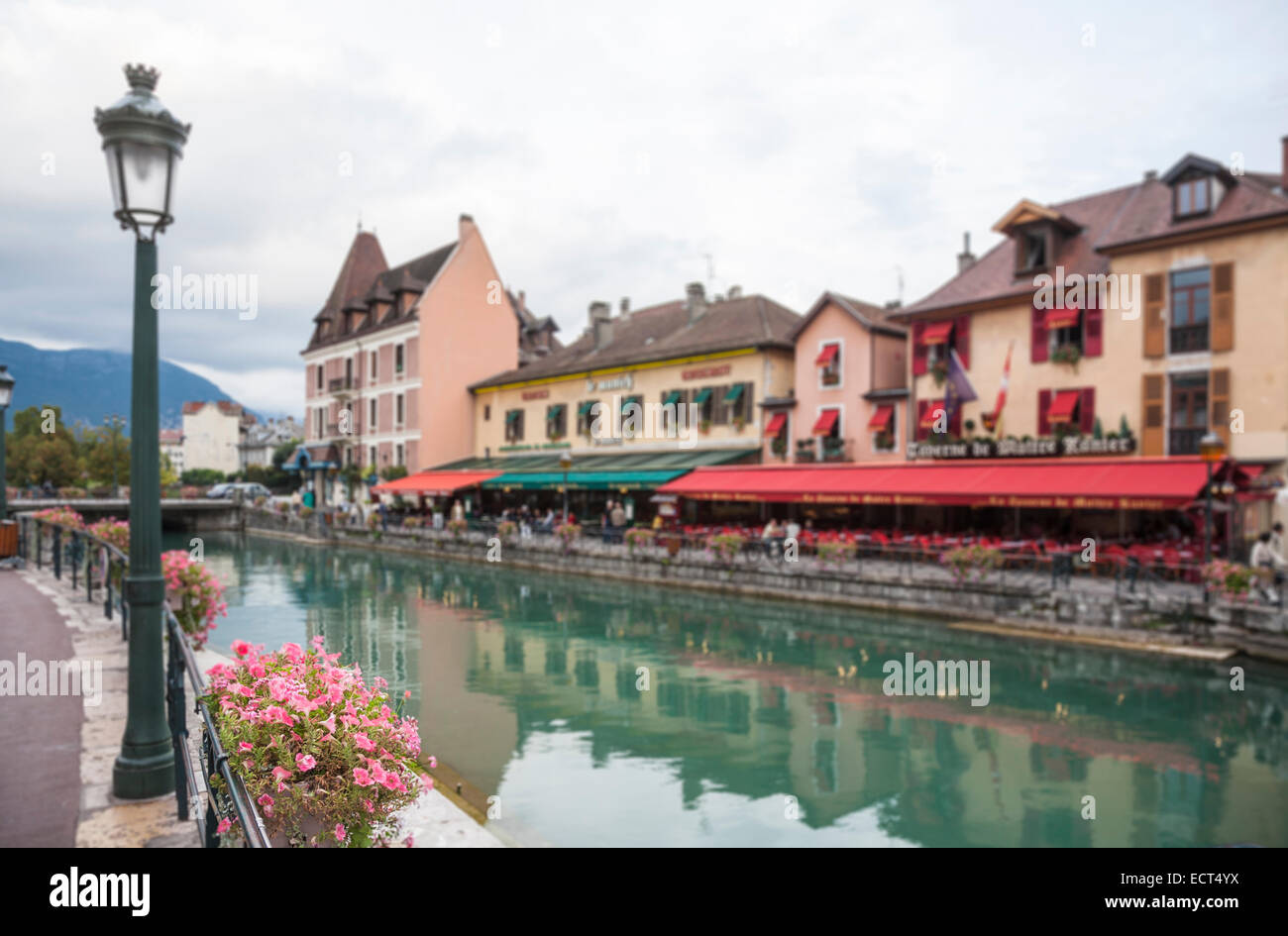 Pretty flower basket on the bank of the Thiou river, restaurants and colourful awnings on far side, old town, Annecy, France Stock Photo