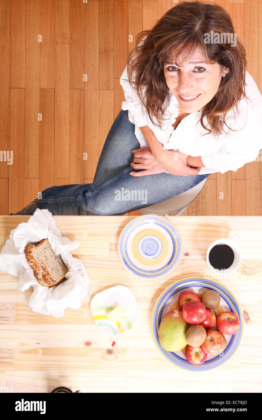 Portrait of a beautiful mature woman sitting in the kitchen Stock Photo ...