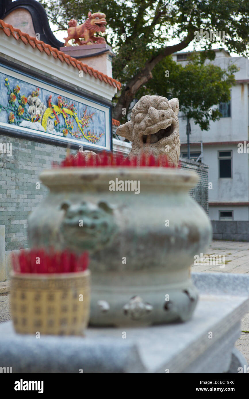 Stone Statue Of A Mythical Chinese Creature Looking Towards Urns Of Burning Incense  At The Buddhist Yuk Hui Temple On Cheung Chau Island, Hong Kong. Stock Photo