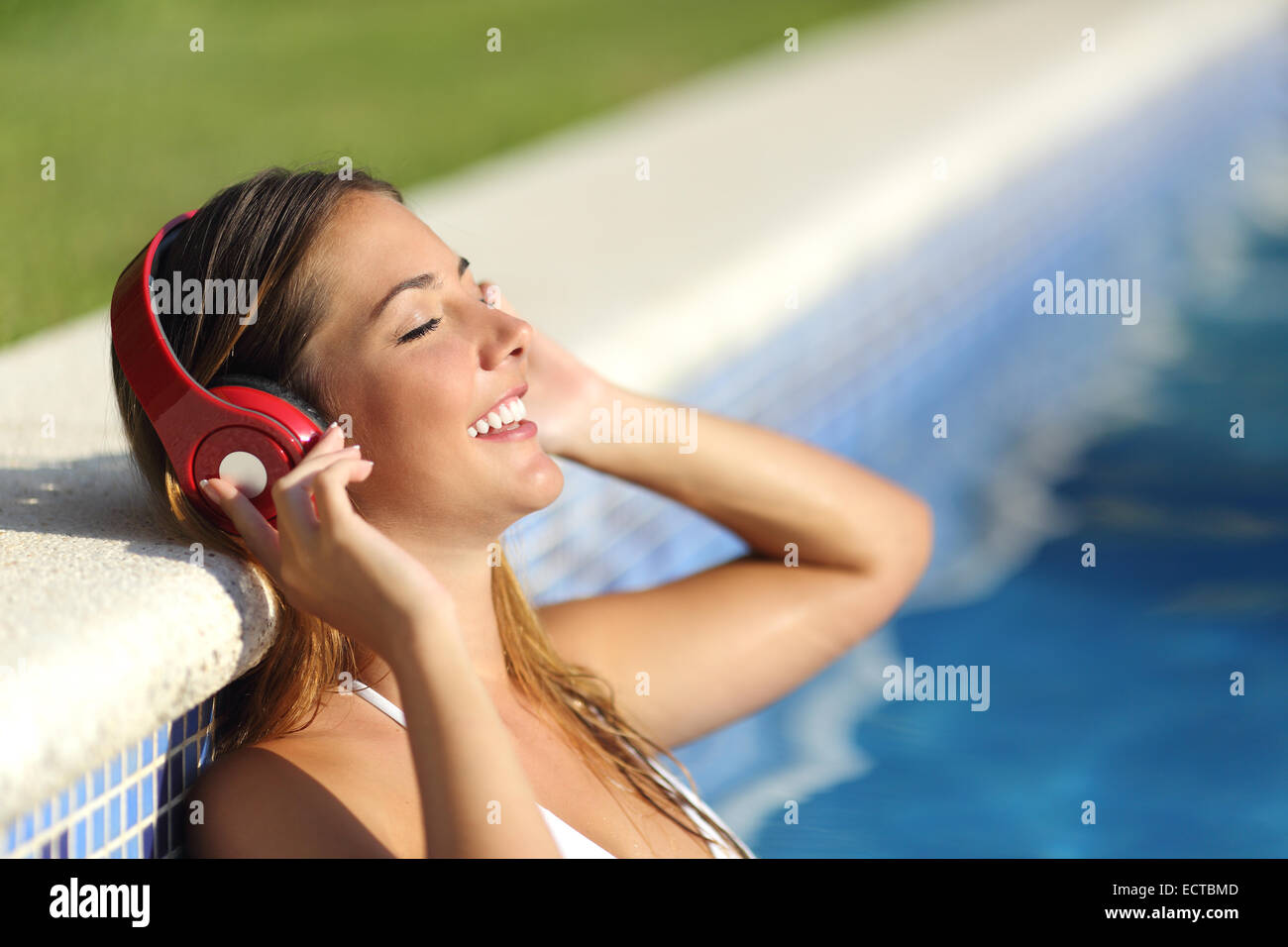 Relaxed woman listening to the music with headphones bathing in a pool Stock Photo