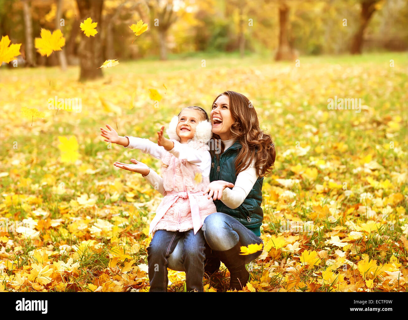 Mother and daughter having fun in the autumn park among the falling ...
