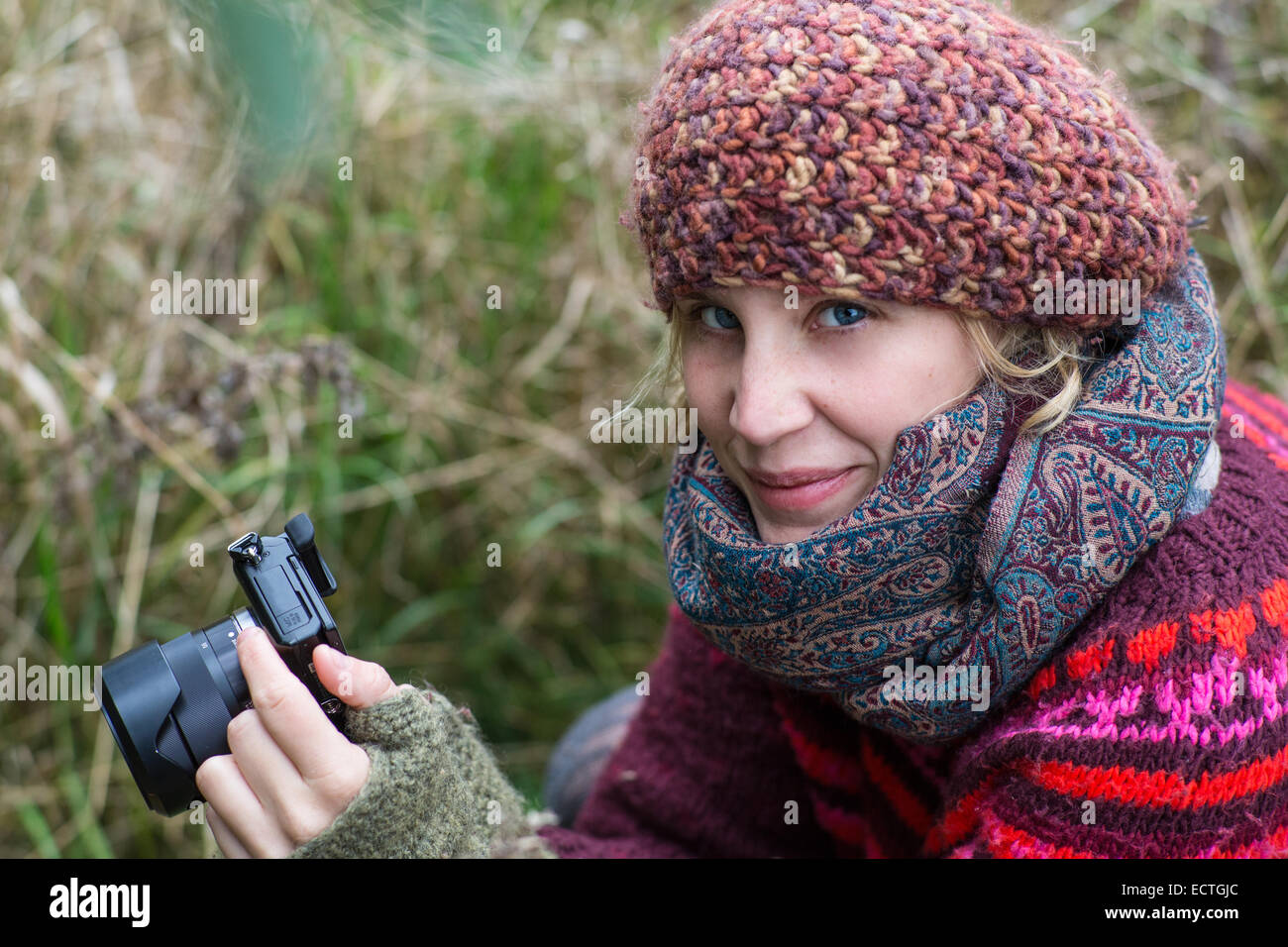 Blond girl with a DLSR camera smiling at the viewer Stock Photo