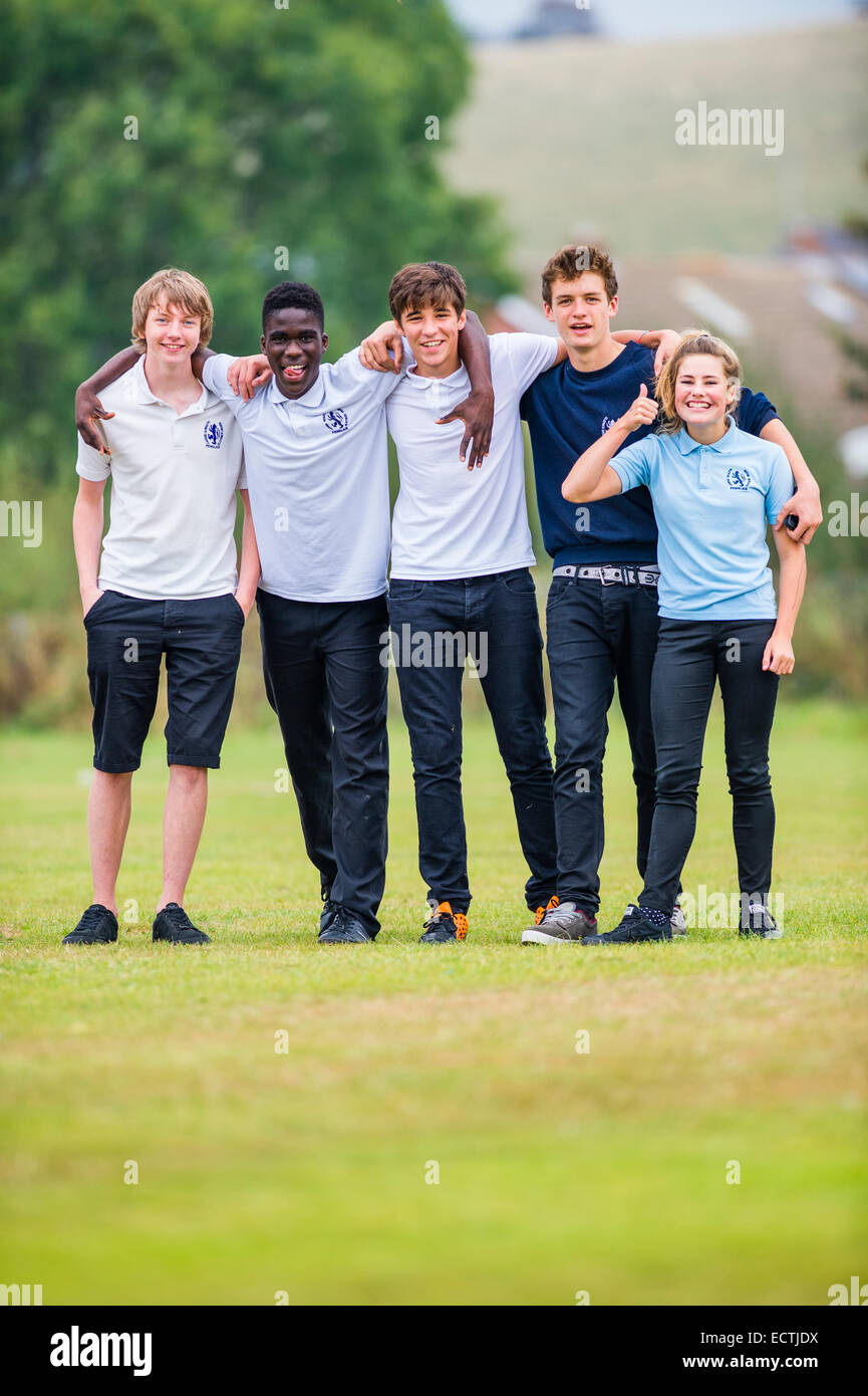 Secondary school education Wales UK: a mixed group of four teenage boys and one girl standing facing ahead with their arms around each other Stock Photo