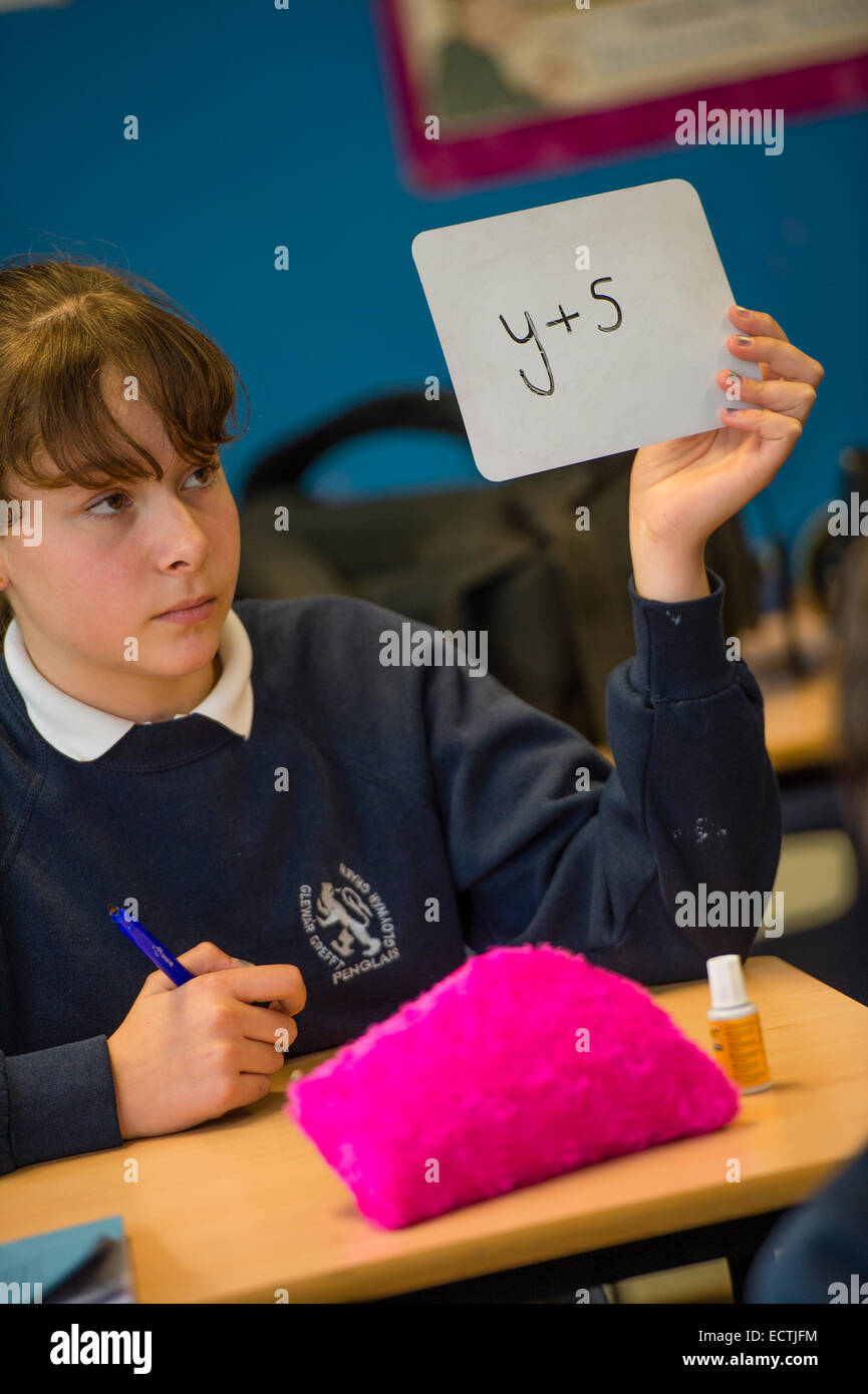 Secondary school mathematics education Wales UK: a girl  holding up cards on which she has written the answers  to algebra problems set by the teacher Stock Photo