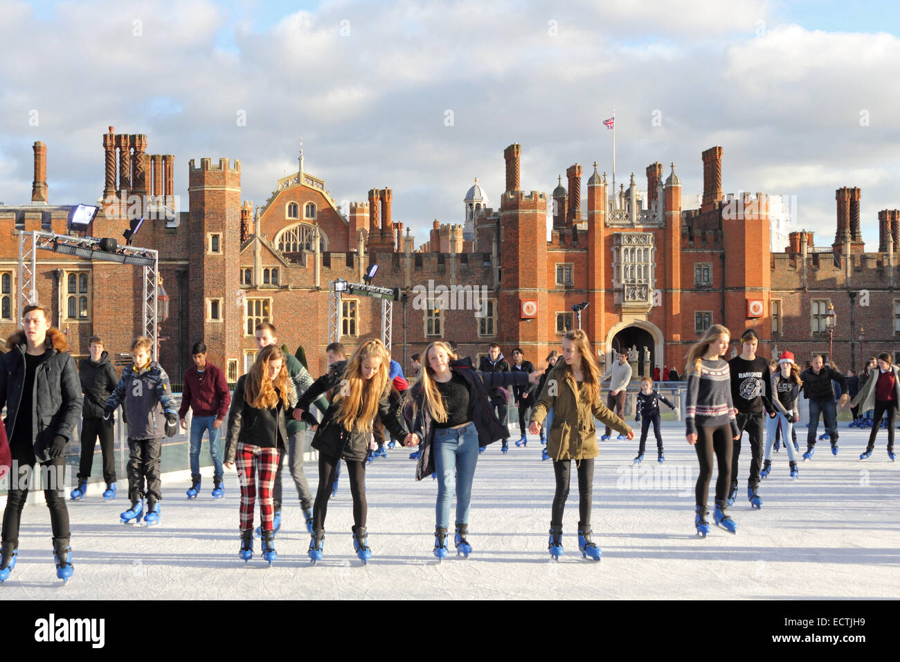 Hampton Court, SW London, England UK. 19th December 2014. On chilly but sunny day in SW London, friends, families and school parties enjoy festive fun at the Ice Rink in the grounds of Hampton Court Palace. It is a magical setting, surrounded by the Tudor Palace of Henry VIII, the River Thames and the gardens of Hampton Court. Credit:  Julia Gavin UK/Alamy Live News Stock Photo