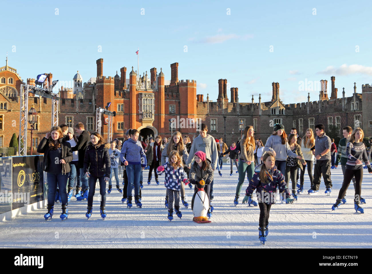Hampton Court, SW London, England UK. 19th December 2014. On chilly but sunny day in SW London, friends, families and school parties enjoy festive fun at the Ice Rink in the grounds of Hampton Court Palace. It is a magical setting, surrounded by the Tudor Palace of Henry VIII, the River Thames and the gardens of Hampton Court. Stock Photo