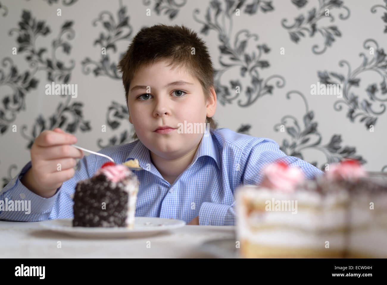 Boy eating cake at table Stock Photo - Alamy