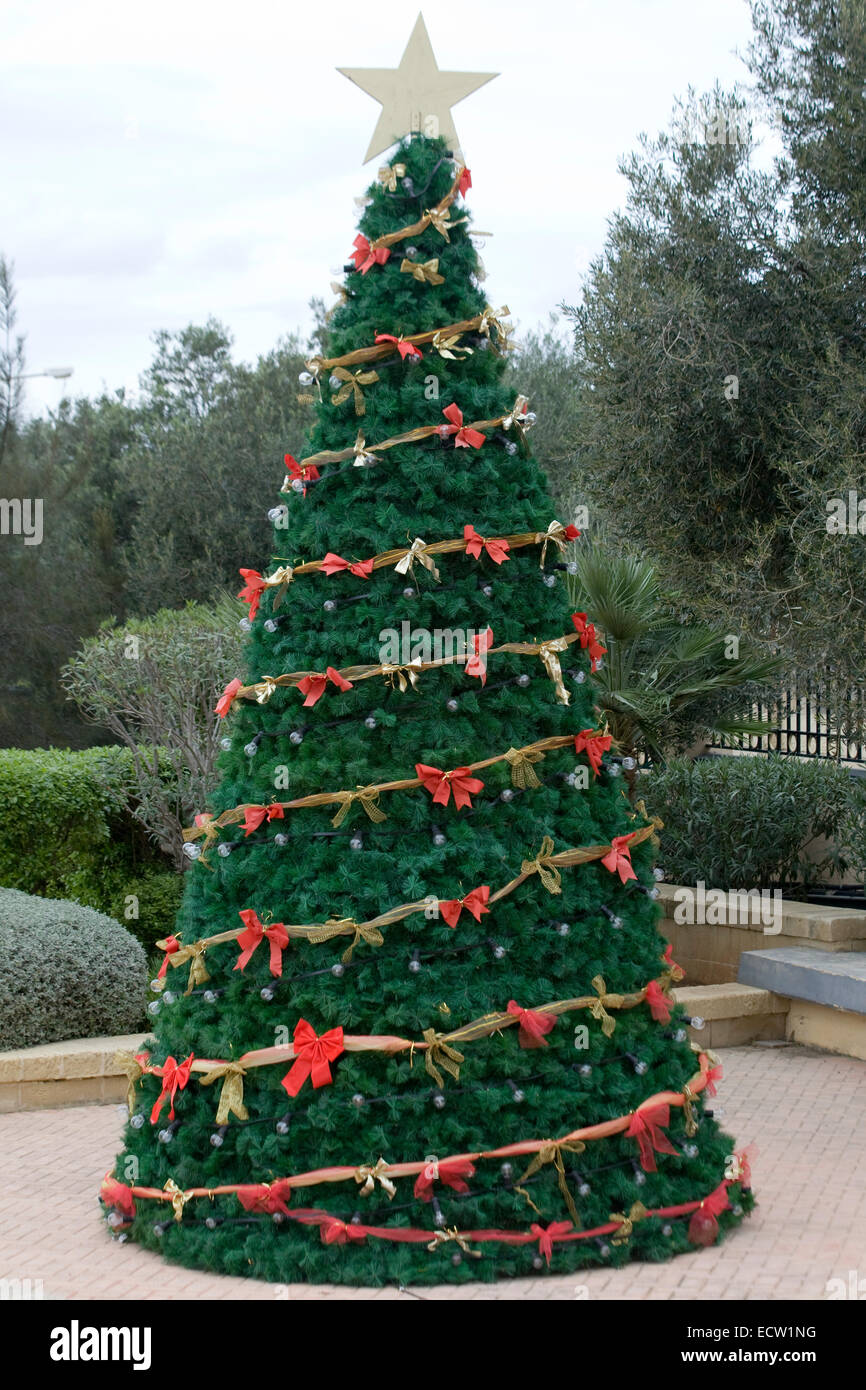 Real Christmas Tree Decorated with Red Bows and fairy lights with a Christmas star on the top Stock Photo