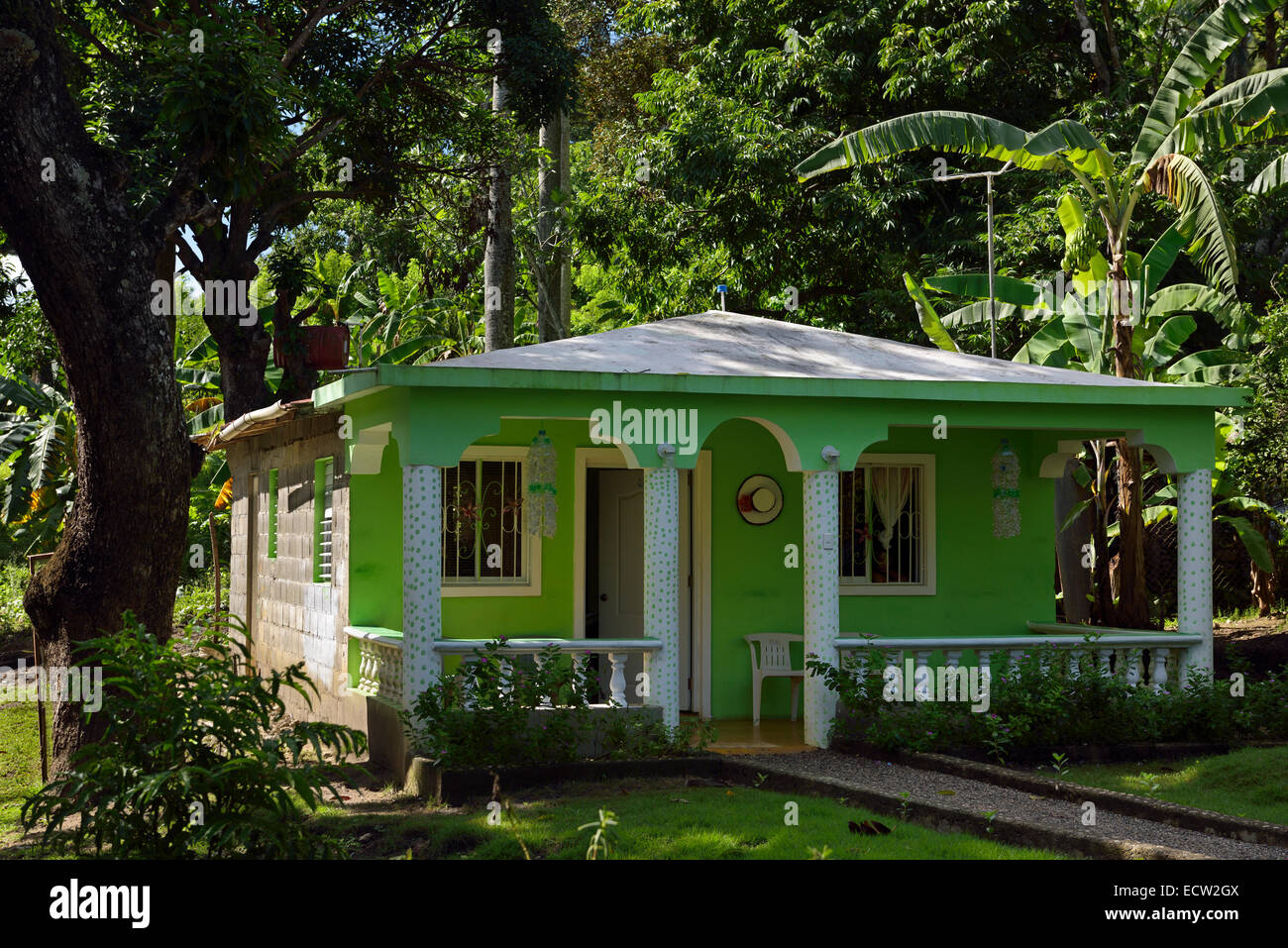 Rural cinder block house painted green in Dominican Republic with garden and jungle Stock Photo