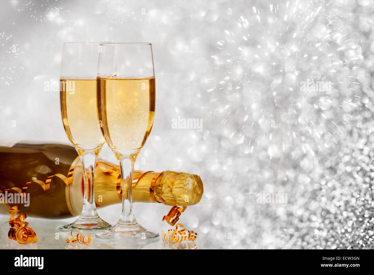 Glasses with champagne and bottle over sparkling holiday background