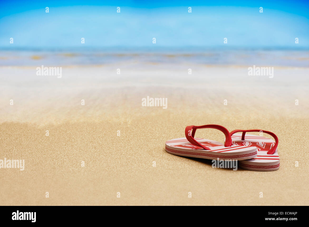 flip flop sandals on a sandy beach with blue sky Stock Photo - Alamy