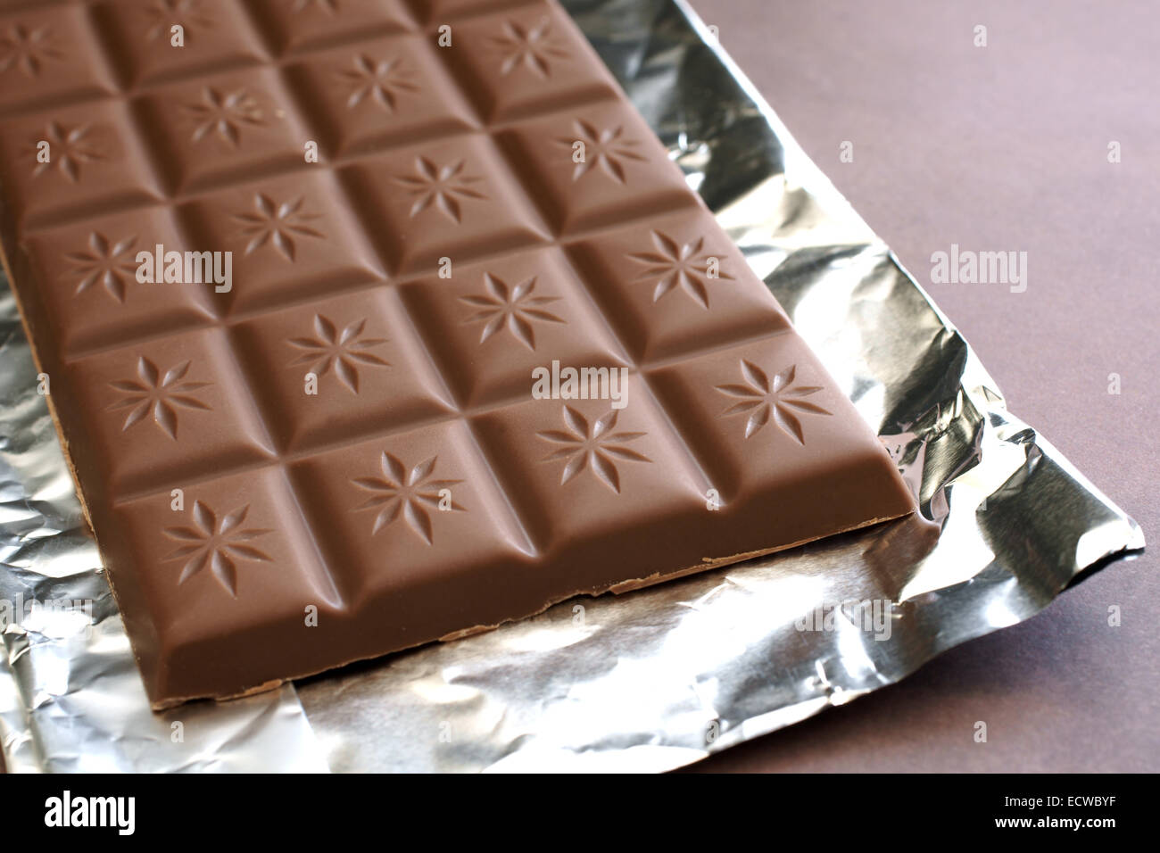Bar of milk chocolate on a foil wrapper Stock Photo
