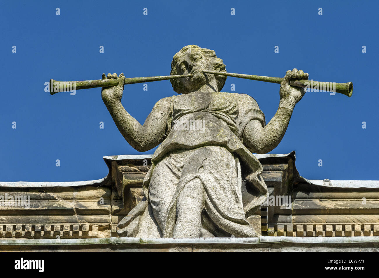 Stone carved statue of a male blowing into two musical pipes. Stock Photo