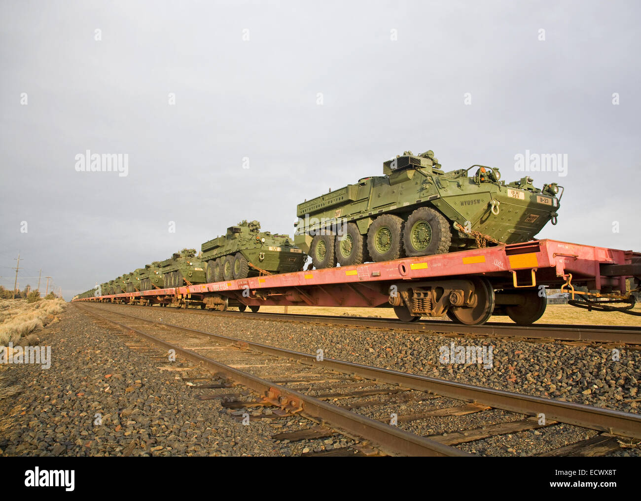 Army personnel carriers and other army vehicles aboard a freight train going south through central Oregon. Stock Photo