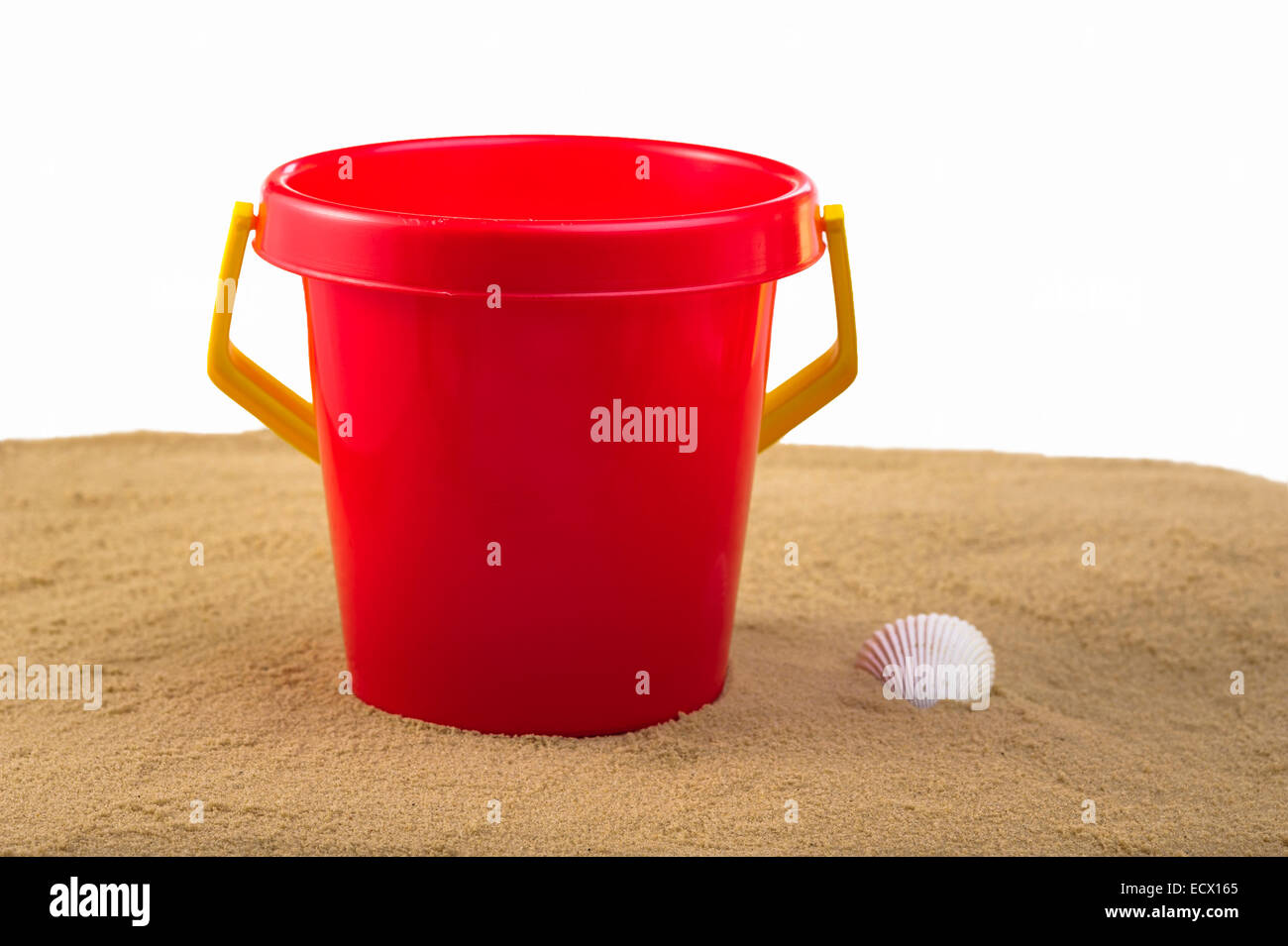 Red plastic bucket, sitting on sand. Stock Photo